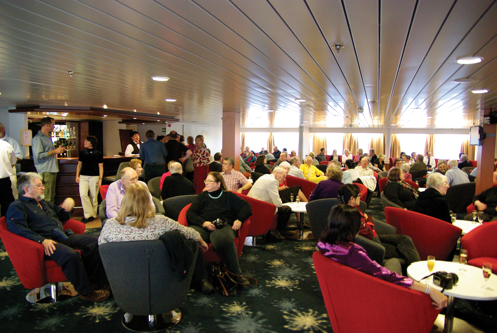 people enjoying a drink and chat in the bar on an antarctic cruise vessel.